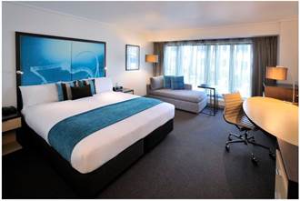 A bedroom with a bed and desk in a room  Description generated with very high confidence